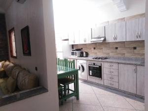 uma cozinha com armários brancos e uma mesa verde em Mirleft Tayought Guest House em Mirleft