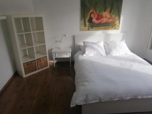 een slaapkamer met een wit bed en een nachtkastje bij Casa Frida in Oostende