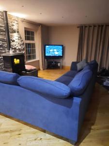 a blue couch in a living room with a television at Radharc an Chuain 2 Bedroom Holiday Home in Galway