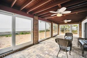 a screened porch with chairs and a ceiling fan at Sunrise Cove - Oceanfront Bliss Luxury Beach Retreat in East Haven
