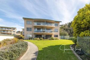 an apartment building with a lawn in front of it at The Salty Seagull – ocean-view luxe! in Encounter Bay