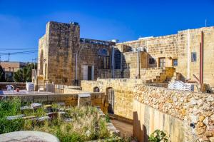 an old stone building with a stone wall at Gabriel Farmhouse Gozo in San Lawrenz