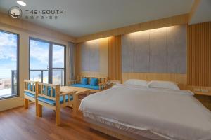 a bedroom with a large bed and a table and chairs at The South-Sunset in Hengchun South Gate