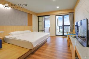 1 dormitorio con 1 cama grande y TV de pantalla plana en 南喃夕語-暮日 en Hengchun Old Town