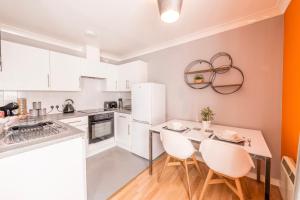 a kitchen with white cabinets and a table and chairs at PRIMEEE LOCATION - Modern Central Apartment in Bristol