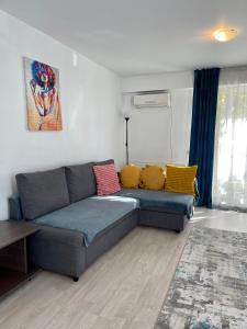 sala de estar con sofá azul y almohadas coloridas en Fly Airport Residences & Therme-SELF CHECK-IN en Otopeni