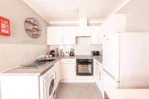 cocina blanca con armarios blancos y lavavajillas en PRIME LOCATION - City Center Apartment, en Bristol