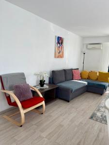 uma sala de estar com um sofá azul e uma cadeira em Fly Airport Residences & Therme-SELF CHECK-IN em Otopeni
