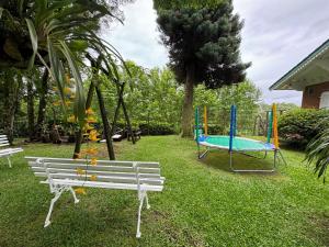 un parque con un banco blanco y un parque infantil en Hotel Pousada Ald' Mama en Gramado