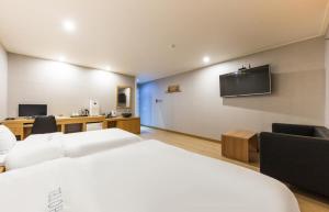 a hotel room with a bed and a tv on the wall at Daesan Hotel in Seosan