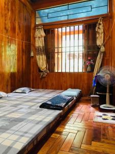uma cama grande num quarto de madeira com uma janela em Khuổi Ky Eco Homestay em Cao Bang