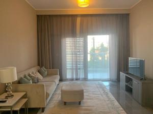 een woonkamer met een bank en een tv bij Contemporary 2-Bedroom Apartment in Al Qurayyah
