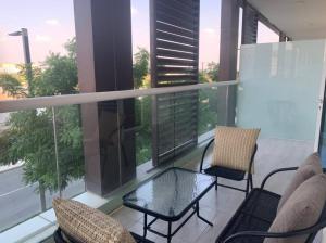 balcón con 2 sillas, mesa y algunas ventanas en Contemporary 2-Bedroom Apartment, en Al Qurayyah