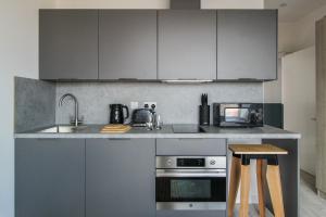 uma cozinha com armários cinzentos, um lavatório e um micro-ondas em The Nest LE1 em Leicester