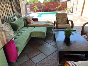 a green couch and two chairs on a patio with a pool at 17 Byvanger Luxury Home Deluxe Queen Suite Room 1 in Centurion