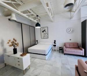 um quarto branco com uma cama e um sofá rosa em Loft Puerta de Capitulares em Córdoba