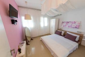 a bedroom with a white bed and a flat screen tv at Uno Apartment 2 in Livadia