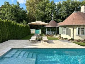 una piscina con sillas y una sombrilla junto a una casa en Elite House en Palić