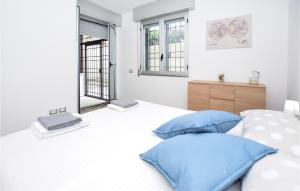 een slaapkamer met een wit bed met blauwe kussens bij Lovely Apartment In Anzio With Kitchen in Anzio