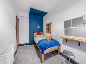 1 dormitorio con cama y pared de acento azul en Nice Cottage In Amble With 3 Bedrooms And Wifi en Amble