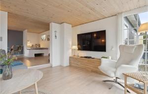 エーベルトフトにあるAwesome Home In Ebeltoft With 2 Bedroomsのリビングルーム(テレビ、テーブル、椅子付)