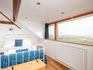 a bedroom with a bed and a large window at Sgwner View in Abererch