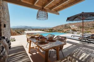 eine Terrasse mit einem Tisch und Poolblick in der Unterkunft Pleiades Villas Naxos2 (Hottub) in Agkidia