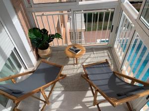 einen Balkon mit 2 Stühlen, einem Tisch und einem Pool in der Unterkunft APTO RESIDENCIAL EN BENICASIM in Benicàssim