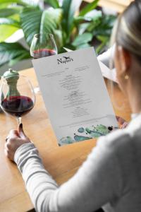 una mujer sentada en una mesa con una copa de vino en voco Oxford Thames, an IHG Hotel en Oxford