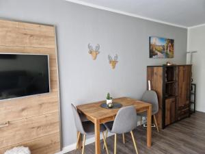 a dining room with a table and chairs and a tv at Apartment am Bocksberg in Hahnenklee-Bockswiese