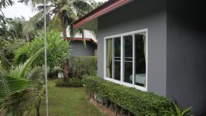 ein graues Haus mit einem Fenster und einigen Pflanzen in der Unterkunft Mindful Kinesics Wellness Living in Nathon Bay