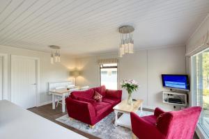 ein Wohnzimmer mit 2 roten Stühlen und einem TV in der Unterkunft 2 bedroom lodge sleeps 4 loch and mountain view in Crianlarich