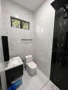 La salle de bains blanche est pourvue de toilettes et d'un lavabo. dans l'établissement THE 99 SUITES, à Kuala Terengganu