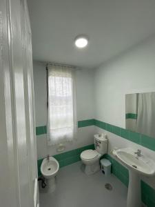 a green and white bathroom with a toilet and a sink at Hotel El Nuevo Semellon 