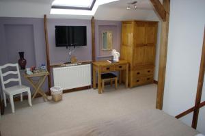 een slaapkamer met een bureau, een tv en een stoel bij Horse and Groom Inn in Banbury