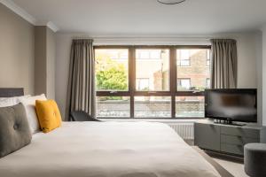 a bedroom with a large bed and a television at Monarch House - Serviced Apartments - Kensington in London