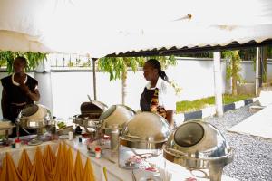 a woman standing next to a table with pots and pans at Mojoh Inn Hotel in Ambira