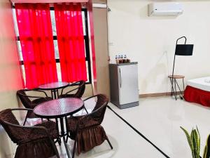 2 Tische und Stühle in einem Zimmer mit roten Vorhängen in der Unterkunft Red Palm Inn studio room with Netflix in Baybay