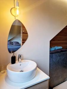 ein Bad mit einem Waschbecken und einem Wandspiegel in der Unterkunft La Cachette de Simone in Spa