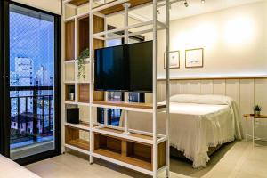um quarto com uma televisão e uma cama em Design FLAT Wifi 1gb frente Ufsc em Florianópolis