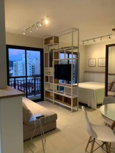 uma sala com um quarto com uma cama e uma televisão em Design FLAT Wifi 1gb frente Ufsc em Florianópolis
