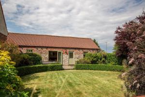 una casa in pietra con tetto rosso e cortile di Stables Cottage a Selby