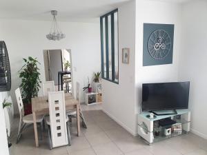 een woonkamer met een televisie en een eettafel bij Sweety house in Brive-la-Gaillarde