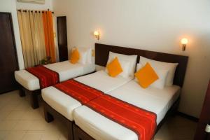 two beds in a hotel room with orange pillows at Gimanhala Hotel in Dambulla