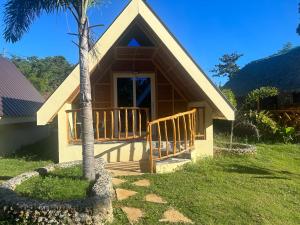 a house with a porch and a palm tree at Dwarf Guest House in Siquijor