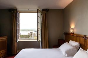 a bedroom with a bed and a large window at La M&egrave;re Poulard in Le Mont Saint Michel