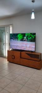 TV de pantalla plana grande en un centro de entretenimiento de madera en Villa Larnaca Bay Resort, en Oroklini