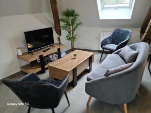sala de estar con 2 sillas, mesa y TV en Serrimmo - appartement Bérangère, en Bléneau