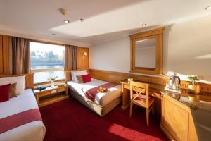 Habitación de hotel con 2 camas, escritorio y espejo. en MS Chateau Lafayette Nile Cruise - 4 nights from Luxor each Monday and 3 nights from Aswan each Friday, en Luxor