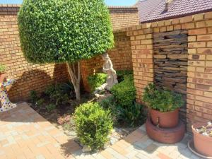 a garden with a tree and a brick wall at Sally's Tranquil Airbnb in Centurion